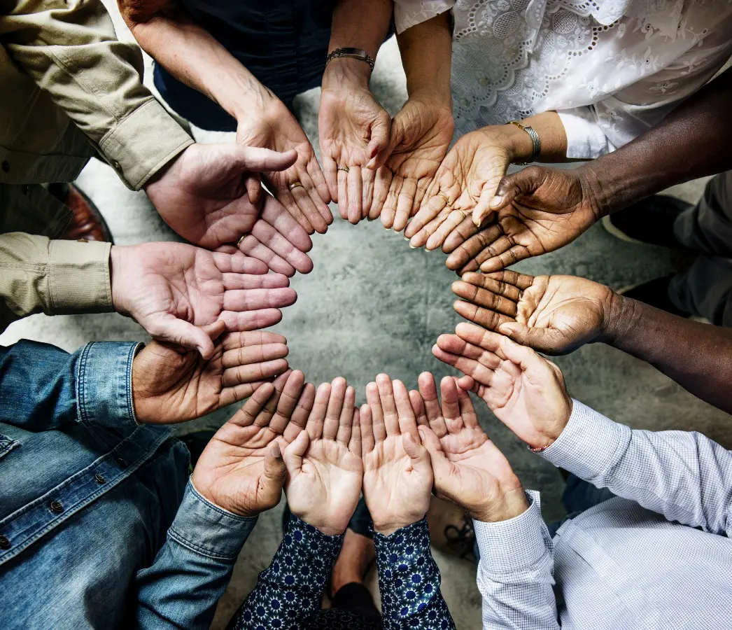 A group of people holding hands in the middle of a circle.