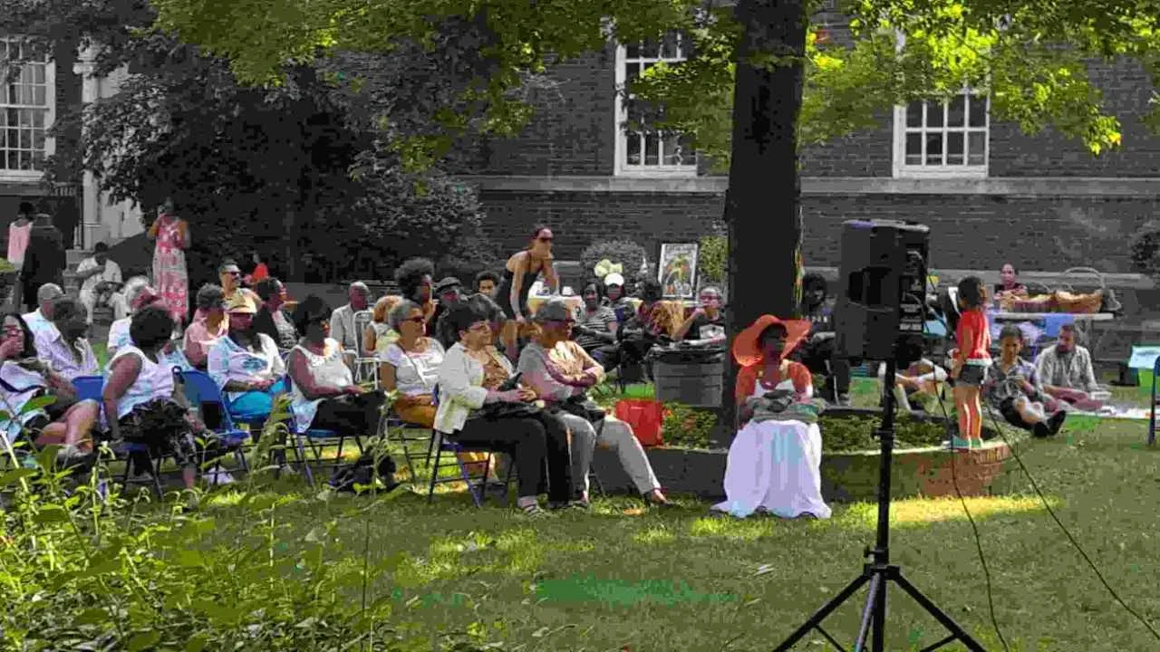 A group of people sitting on chairs in the grass.